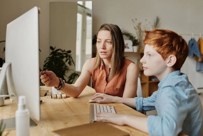 A women is explaining something on computer to a student