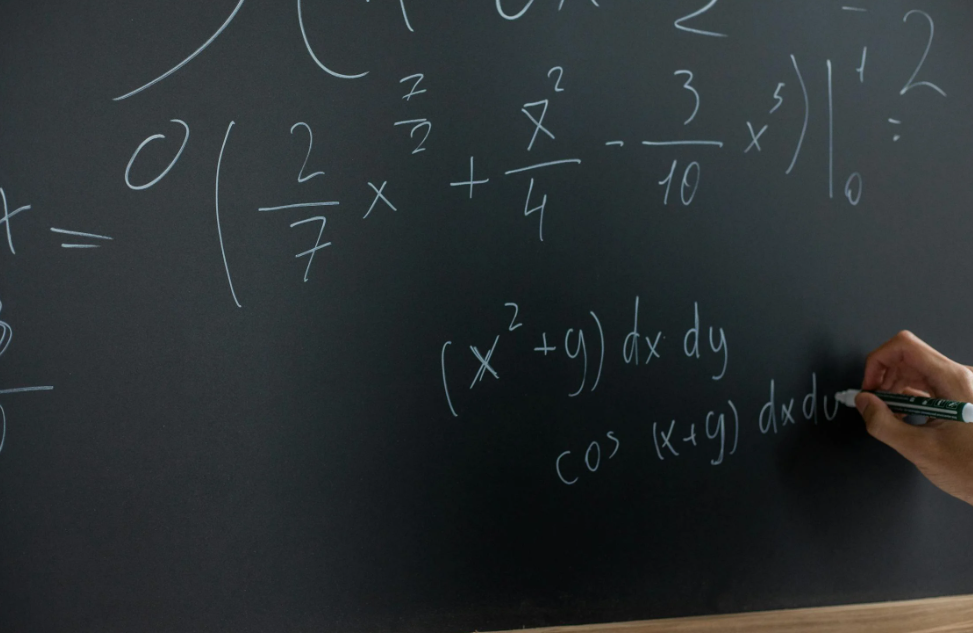 A teacher solving mathematical equations on blackboard.